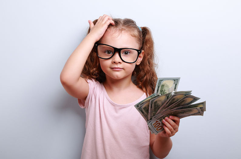 A young girl wearing glasses and a pink shirt is scratching her head while holding money and trying to figure out an event planning budget